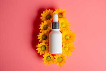 Cosmetic product in tube, bottle, lotion or serum and yellow marigold flowers isolated on pink background. 