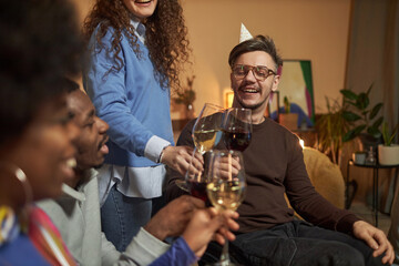 Portrait of man with disability clinking wine glasses while toasting with friends and celebrating together