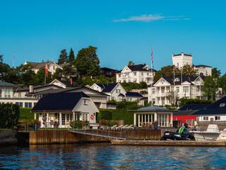 Fototapeta na wymiar Waterfront view on a white houses on a shore in Oslo fjord. Norwegian detached houses
