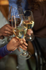 Vertical closeup of hands holding wine glasses and toasting while celebrating holiday together