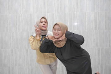 The smiling expression of two Asian Indonesian women wearing hijabs wearing black and yellow clothes
