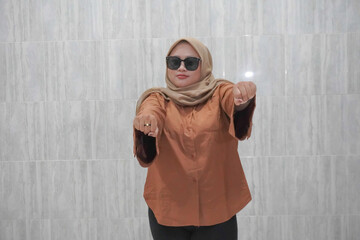 Smiling expression of Asian Indonesian woman in hijab wearing orange shirt