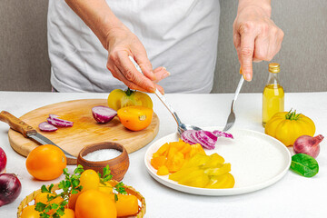 A woman is preparing a tomato salad. Ripe vegetables, herbs, aromatic spices, olive oil