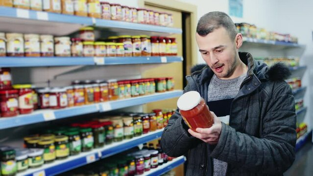 Man shopper wants to buy jar of delicious lecho in a grocery store. High quality 4k footage