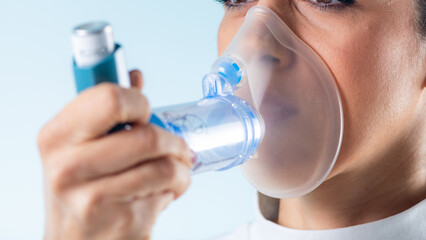 Woman manages her asthma with an inhaler featuring an extension tube for enhanced accessibility and...