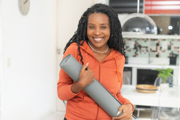 Beautiful black woman with yoga mat ready for class at gym