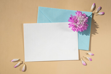 Beautiful little violet flowers on postal blue envelope on beige background, empty paper note copy space for text, spring time, greeting card for holiday. Flower delivery
