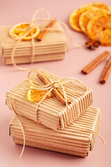 Craft handmade gift boxes made of zero waste recycled carton material tied with thread bow decorated with dried orange citrus fruit slice and cinnamon stick used as eco friendly holiday present