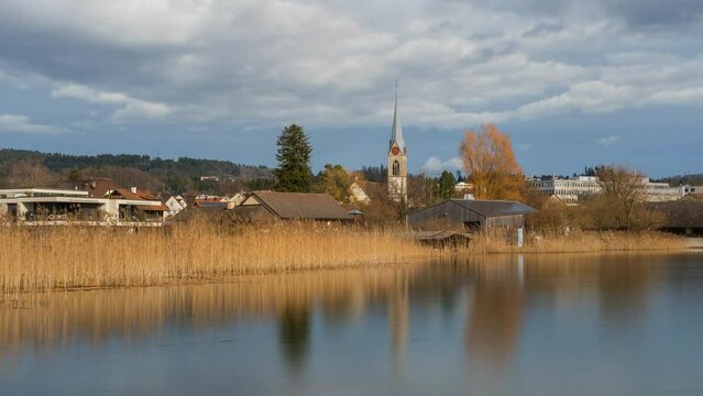 Clouds move over a church near a lake in Switzerland.