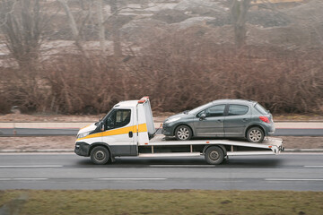 A tow truck helps a broken car on the highway. The car has been damaged by a collision and needs to...