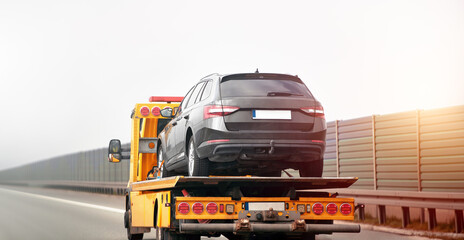 Car breakdown and towing. A tow truck with a broken car on a speedway road. Towtruck transporting a...