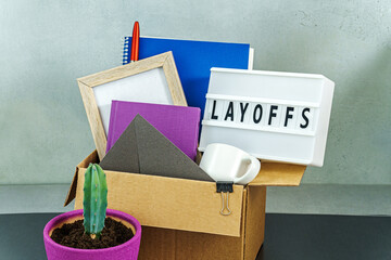 Cardboard box full of office stuff and personal items with lamp with text layoffs - 750437979