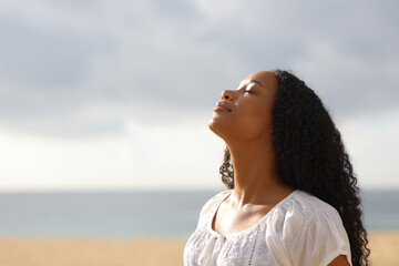 Black woman breaths on the beach a cloudy day