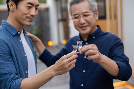 Mid adult man drinking Chinese spirits with his father