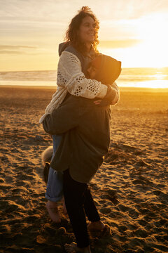 Young man carrying happy woman at beach