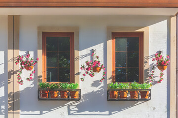 Fototapeta na wymiar Two charming windows adorned with vibrant flower boxes bask in the Turkish sun, reflecting the quaint beauty typical of local architecture. Side city, Manavgat, Turkiye (Turkey)