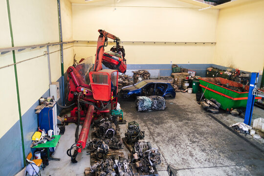 Mechanic operating crane machine to carry scrap vehicles at workshop