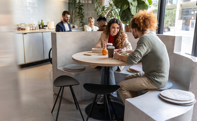 Business colleagues having lunch sitting on seat at office cafe