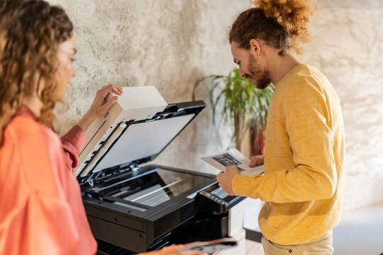 Businessman using photocopier machine with colleague at office