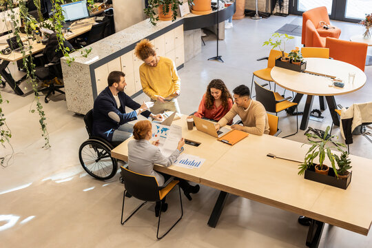 Businessman working with colleagues sitting at desk in office