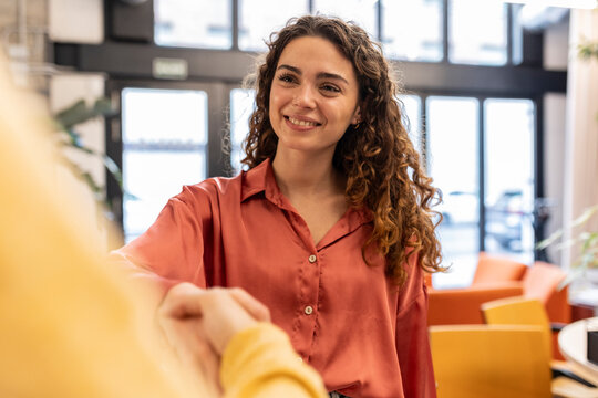 Smiling businesswoman doing handshake with colleague at office - Powered by Adobe