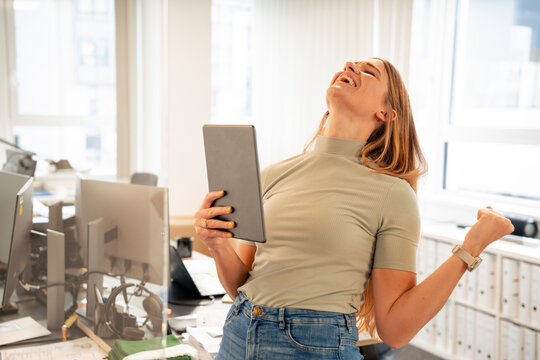 Excited businesswoman with tablet PC celebrating success in office