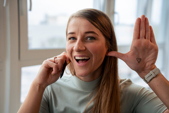 Cheerful businesswoman showing heart drawn on palm in office