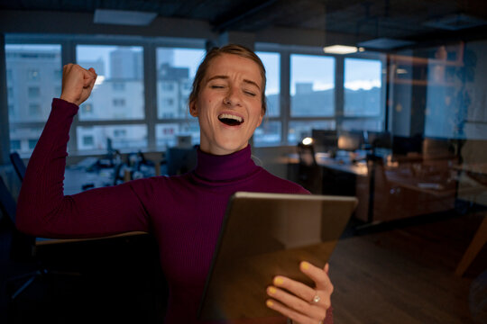 Excited businesswoman with tablet PC celebrating success in office
