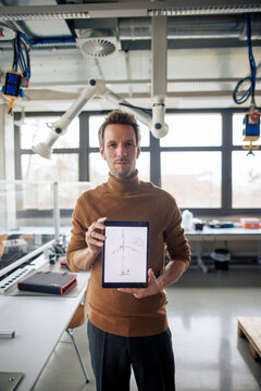 Engineer showing tablet PC with wind turbine sketch on display at workshop