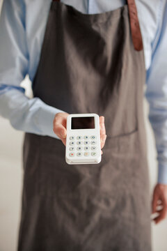 Engineer wearing apron and holding credit card reader at workshop