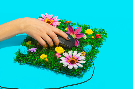 Businesswoman holding computer mouse on flowerbed against blue background