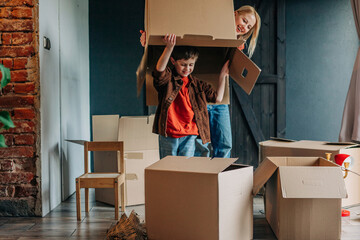 Happy woman with son holding empty cardboard box over head