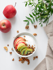 Healthy breakfast. Homemade granola or muesli with apple, kiwi and nuts in a bowl on a white background.