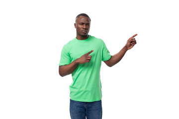 Naklejka premium american brunette man with short haircut dressed in a light green t-shirt points his hand to the side advertising space
