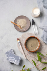 Organic cosmetic with blue clay on a marble board with brush, candle, soap and eucalyptus branch on a light background.