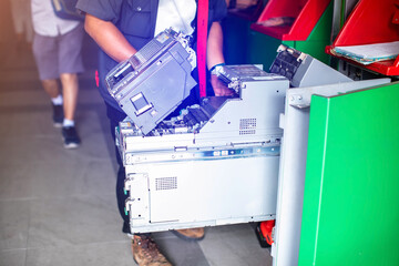Staff is performing maintenance on an ATM machine. Officer is putting money into an automated...