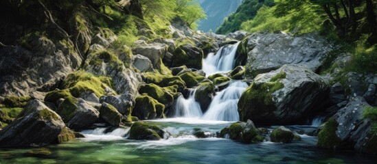Serene miniature waterfall cascading in a rocky alpine stream under mountain backdrop