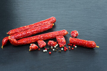 long sticks sousages with red hot peppers on black stone