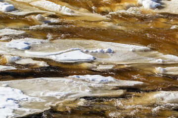 Melting ice and flowing water in the river during early spring time. River Keila, Estonia