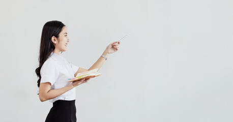 Female asian student holding a book standing on a white background.