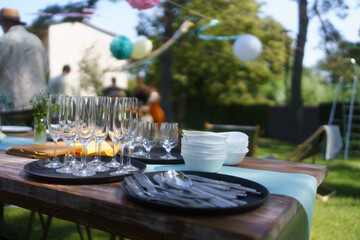 Close up shot of empty wine glasses, cutlery and utensils at summer garden party.