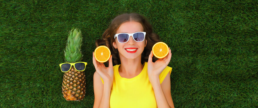 Summer portrait of happy smiling young relaxing woman with fruits lying on grass in the park