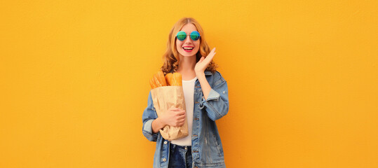 Happy cheerful smiling young woman holding grocery shopping paper bag with white bread baguette - Powered by Adobe