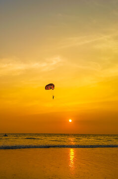 Parasailing extreme sports on beach in sunset background. Paragliding in front of an amazing sunset. A beautiful background of a parasailing parachute on the backdrop a sunset on an evening sky.