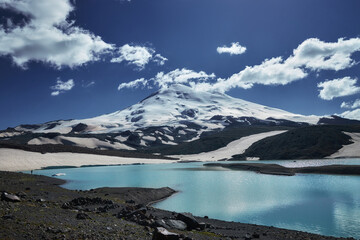 Caucasus Elbrus majestic mountain peak, blue sky lake, snow covered glacier, rocky landscape, alpine scenery