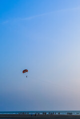 Parasailing extreme sports on beach in blue sky background. Man is parasailing in the blue sky. Paragliding in the clear sky above the sea.