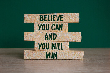 Motivational concept Believe You Can And You Will Win on brick blocks Beautiful green background,...