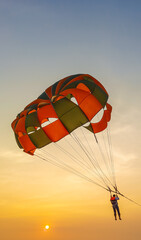 Obraz premium Parasailing extreme sports on beach in blue sky background. Man is parasailing in the blue sky. Paragliding in the clear sky above the sea.