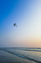 Parasailing extreme sports on beach in blue sky background. Man is parasailing in the blue sky. Paragliding in the clear sky above the sea.