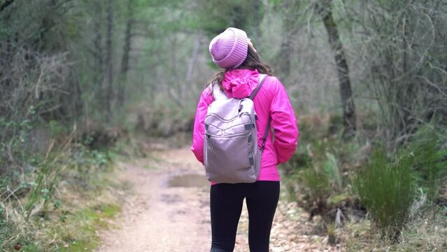 Hiker girl, woman outdoors in mountain forest, nature walking, strolling, wandering at the woods on winter.